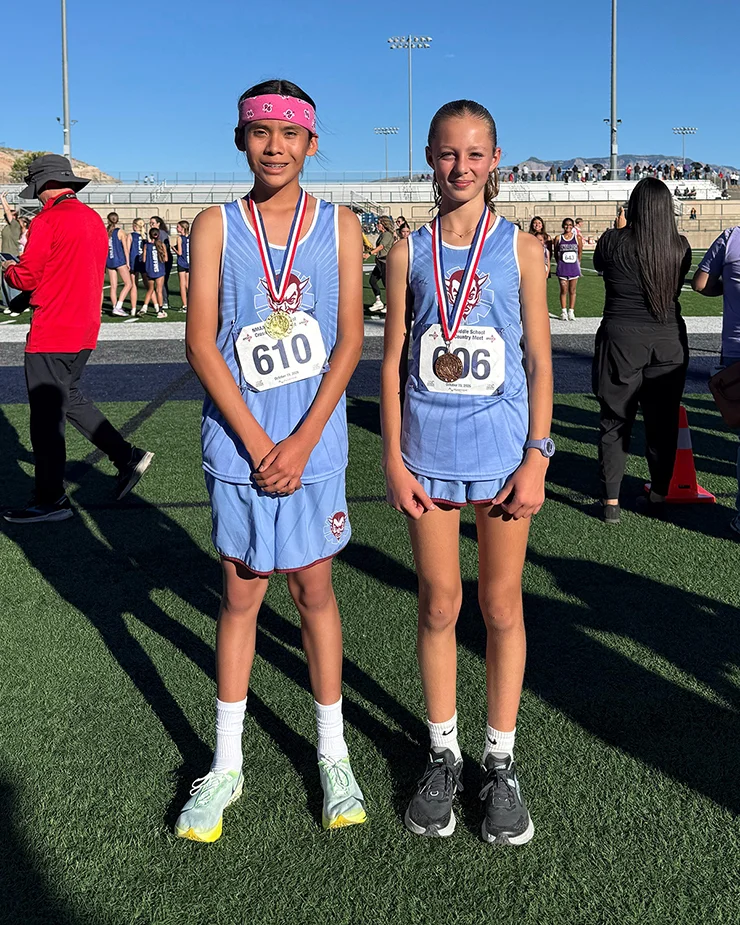 Two student runners pose with medals
